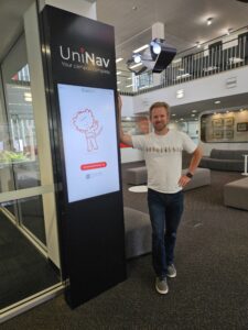 Standing with the UniNav kiosk in the Morris Miller library, Sandy Bay campus